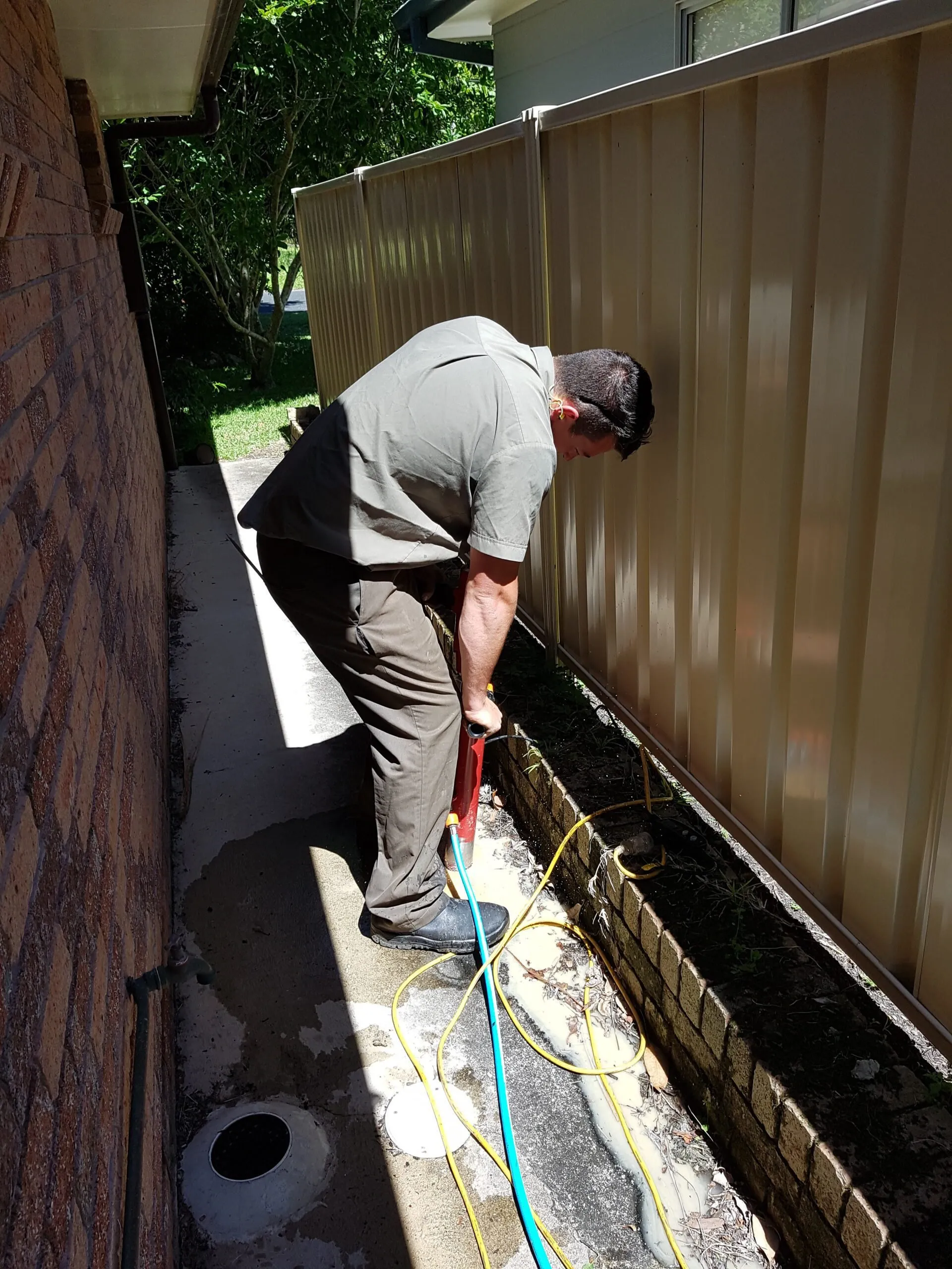 A technician core-drilling a path to install termite bait stations