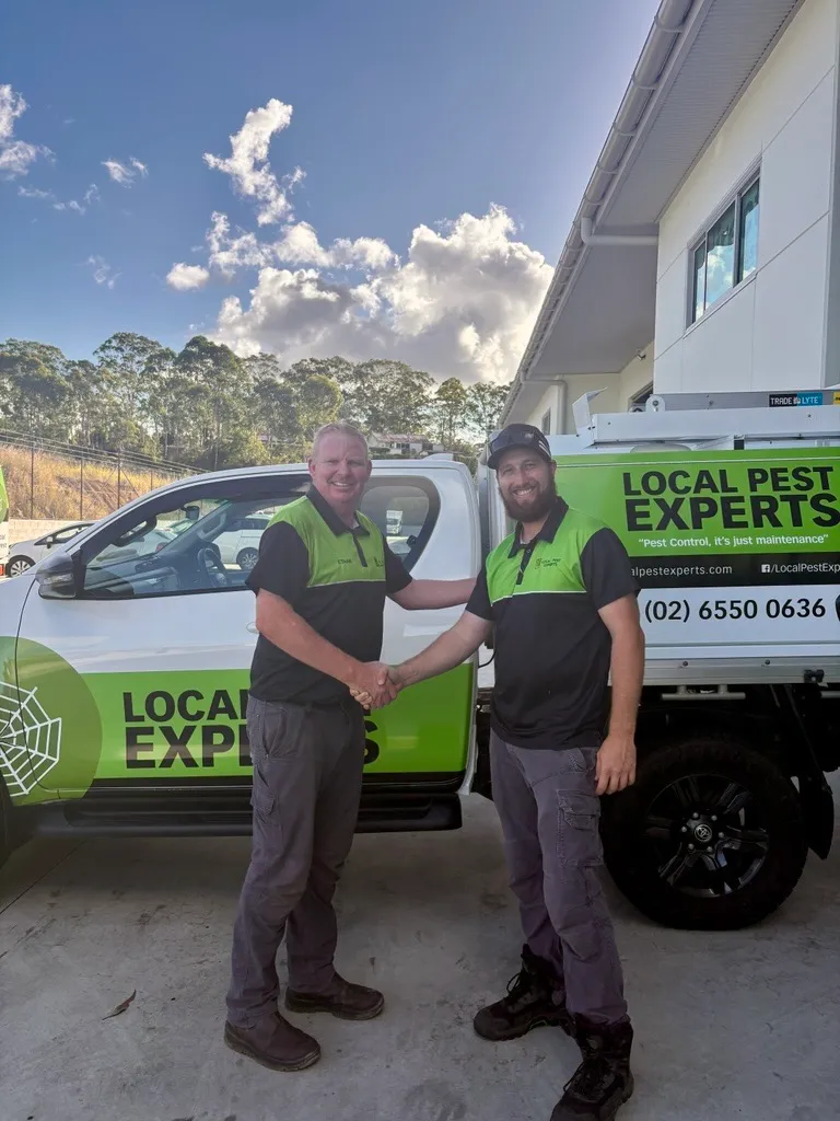Two Local Pest Experts technicians shaking hands in front of a branded ute