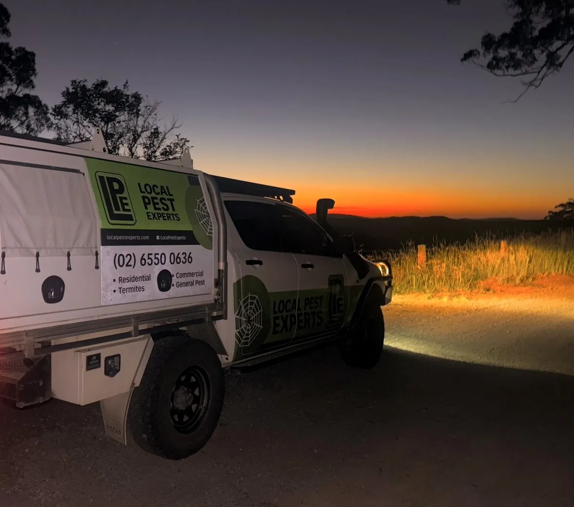 A Local Pest Experts ute at a lookout at dusk, with an orange sunset over the hills